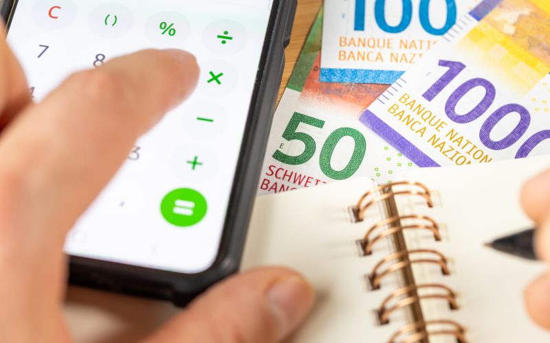 Swiss francs, Counting on smartphone calculator, CHF money, notes in notebook. Financial settlement, Household budget, Taxes, Switzerland currency exchange rate, Business Financial Analysis Concept